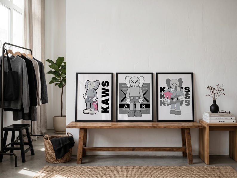 Puede incluir: Tres impresiones art&iacute;sticas enmarcadas con el personaje KAWS en varias poses. Las impresiones est&aacute;n en marcos negros y descansan sobre un banco de madera. El personaje KAWS es gris con huesos cruzados blancos para los ojos y la boca.