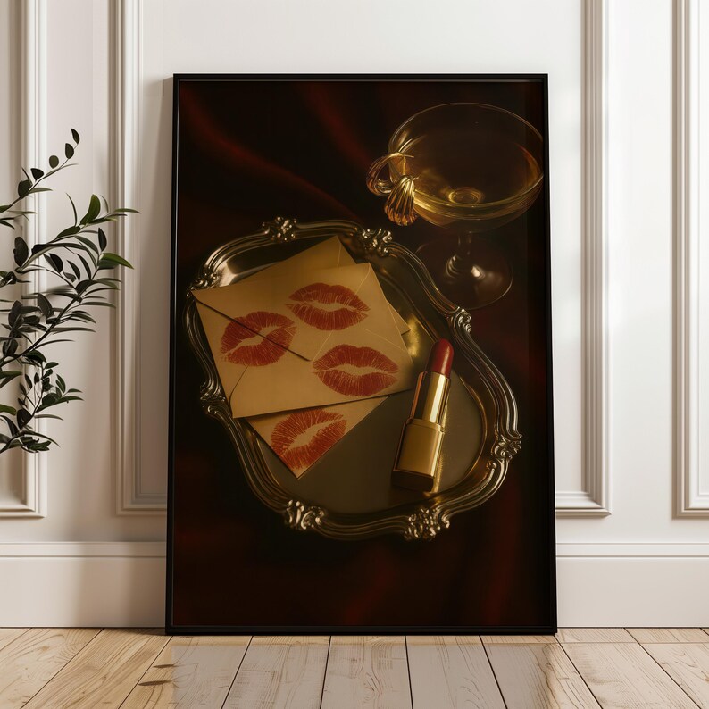 May include: A framed print showing a still life with a vintage silver tray holding lipstick, envelopes with red lip prints, and a champagne glass. The lipstick is gold, and the envelopes are tan.