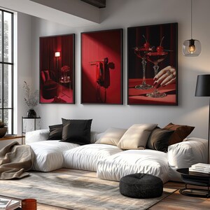 Peut inclure: Un triptyque d'impressions d'art encadr&eacute;es avec des images rouges et noires. L'une montre un cocktail aux cerises, une autre un int&eacute;rieur rouge, et la troisi&egrave;me un objet rouge. Au-dessus d'un canap&eacute; blanc avec des coussins noirs et beiges.