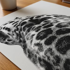 May include: Black and white art print of a jaguar's head and upper body. The illustration features detailed fur texture and distinctive dark spots on a light background. The artwork is a close-up view of the animal's side profile.
