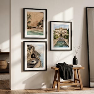 May include: Three framed wall art prints displayed on a white wall. The top left print shows a swimming pool by a building, the bottom left shows a car on a coastal road, and the right print shows a villa with a pool. A wooden bench sits below.