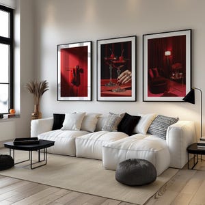 Peut inclure: Trois impressions d'art encadr&eacute;es avec des cadres noirs sont accroch&eacute;es au-dessus d'un canap&eacute; blanc. Les impressions pr&eacute;sentent des images sur le th&egrave;me du rouge, notamment des cocktails aux cerises, un rideau rouge et un objet rouge. Le salon a un tapis neutre, une table basse noire et une lampe de sol noire.
