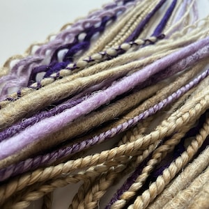 May include: A bundle of synthetic hair extensions in shades of light brown, purple, and lavender. The hair is braided and ready to be added to a person's hair.