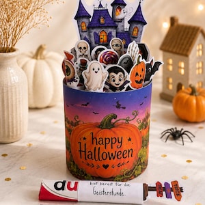 Könnte beinhalten: Ein zylindrischer Halloween-Behälter mit einem großen orangefarbenen Kürbis und dem Text happy Halloween. Er ist gefüllt mit Aufstellern eines violetten Spukschlosses, Geistern, einem Vampir, einem Totenkopf und einer Mumie. Zwei Riegel liegen davor.