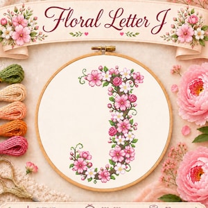 Può includere: Uno schema a punto croce della lettera J formata da fiori di ciliegio rosa e bianchi in un telaio da ricamo in legno. Il design include cinque matassine di filo da ricamo nei colori verde, beige, pesca, arancione e rosa, e forbici dorate.