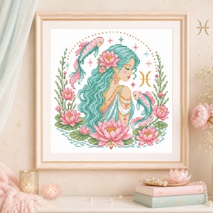 Könnte beinhalten: Ein gerahmtes Kreuzstichmuster mit einer Figur mit langem türkisfarbenem Haar, umgeben von rosa Lotusblüten und zwei Koi-Fischen. Das Design enthält das goldene Sternzeichen-Symbol Fische, kleine Sternakzente und eine kreisförmige Bordüre.
