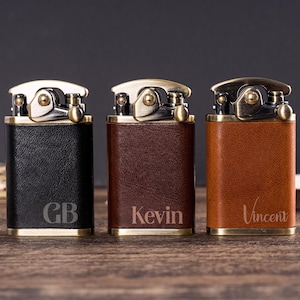以下が含まれることがあります： 真鍮のアクセントと革で覆われたボディが特徴の、パーソナライズされたライター3つ。ライターは黒、茶色、タン色で、「GB」、「Kevin」、「Vincent」のいずれかの名前またはイニシャルが刻まれています。