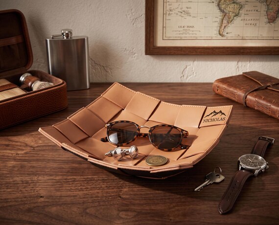 Hand-stitched woven leather valet tray that actually looks like a craftsperson made it — the woven texture elevates it well beyond the flat laser-engraved leather slabs flooding this category.