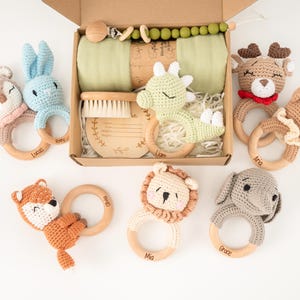 Pode incluir: Um conjunto de presentes para bebês com mordedores de animais de crochê, incluindo um coelho, um veado, uma raposa, um leão e um elefante. O conjunto também contém uma escova, um prendedor de chupeta e um cobertor verde.