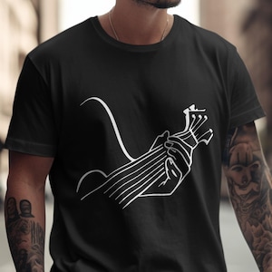 Könnte beinhalten: Schwarzes T-Shirt mit einer weißen Strichzeichnung einer Hand, die eine Ukulele hält. Das Design zeigt Hals, Saiten und Kopfplatte des Instruments. Das T-Shirt hat ein minimalistisches Design.