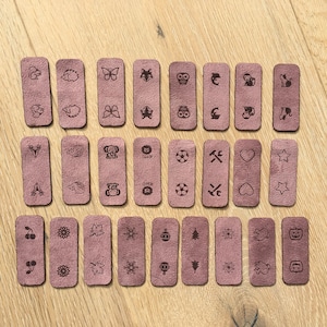 May include: Set of 24 brown leather tags with various animal, nature, and holiday-themed designs. The tags are rectangular and have a brown leather texture.