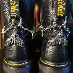 May include: Black leather boots with yellow "AirWair" straps and silver chains and charms, including a moth design.