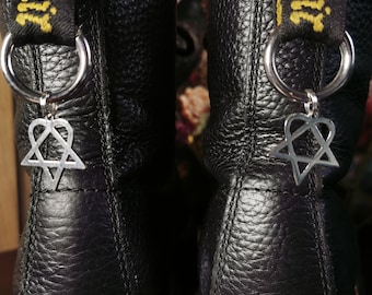 May include: A pair of black leather boots with yellow stitching and a black and yellow strap with the text "Dr. Martens" on each boot. Each boot has a silver charm attached to the strap with a heart and star design.