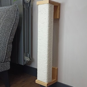May include: A wall-mounted cat scratching post. The post is rectangular, made of tightly wound white rope, and framed with light-colored wood. It is designed to be mounted vertically on a wall, providing a surface for cats to scratch and play.