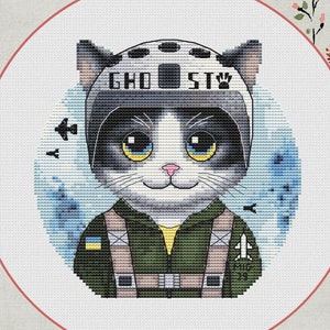 Może przedstawiać: Wzór haftu krzyżykowego przedstawiający kota w kasku pilota z napisem "GHOST". Kot ma czarno-białe futro, żółte oczy i nosi zielony kombinezon lotniczy. Projekt zawiera niebieskie tło i napis "MiG-29".