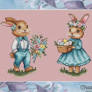 May include: A cross stitch pattern featuring two bunnies, one holding a bouquet of flowers and the other holding a basket of colorful eggs. The bunnies are dressed in blue and white clothing and have brown fur. The background is a light pink color.
