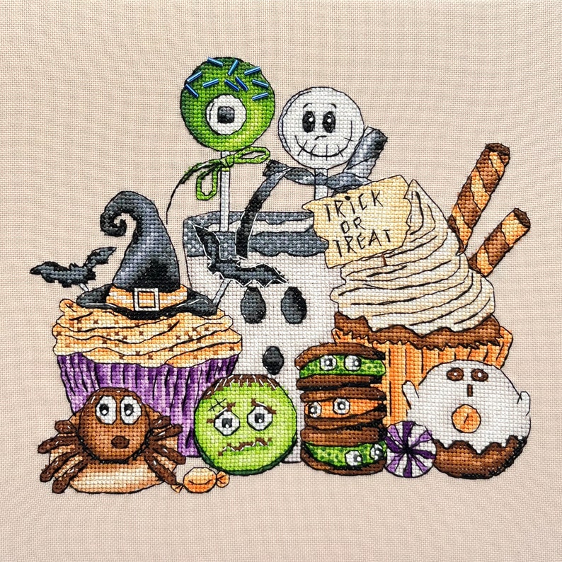 Puede incluir: Un dise&ntilde;o de punto de cruz con tem&aacute;tica de Halloween que presenta una variedad de golosinas, que incluyen cupcakes, galletas y una piruleta. El dise&ntilde;o tambi&eacute;n incluye un sombrero de bruja, un fantasma y una ara&ntilde;a.