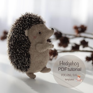 May include: A handmade felt hedgehog with a light brown body and dark brown spiky back. The hedgehog has small black eyes and a pink blush on its cheeks. Text on the image reads "Hedgehog PDF tutorial" with file type options.