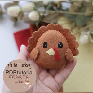 May include: A handmade felt turkey with a brown body, a fan of brown and orange feathers, and a red wattle. The turkey has black eyes and a yellow beak. The text "Cute Turkey PDF tutorial" is on the image. This is a craft project.