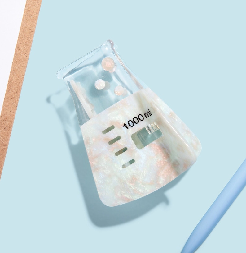 Op de afbeelding: Een witte, iriserende beker met een 1000 ml markering. De beker is gemaakt van helder plastic en heeft een textuur.