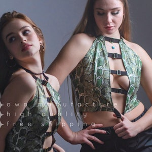 Op de afbeelding: Een groene en zwarte haltertop met een slangenprint en verstelbare bandjes. De top heeft een lage halslijn en een uitsparing aan de voorkant.