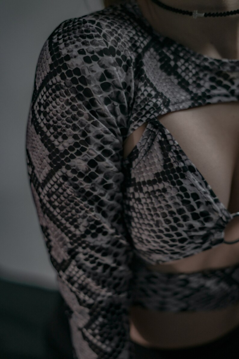 K&ouml;nnte beinhalten: Ein Oberteil mit Schlangenhautmuster in Schwarz und Wei&szlig; mit Ausschnitten an Schultern und Taille.
