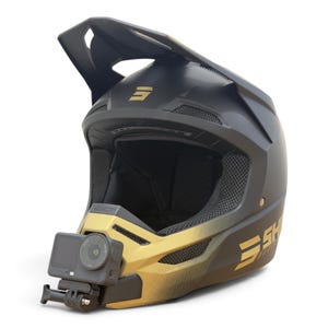 Könnte beinhalten: Ein mattschwarzer und goldener Motocross-Helm mit einem markanten Visier, Belüftungsöffnungen und einer schwarzen Action-Kamera, die sicher am Kinnbügel befestigt ist. An der Seite des Helms steht der Markenname SHOT in goldener Schrift.