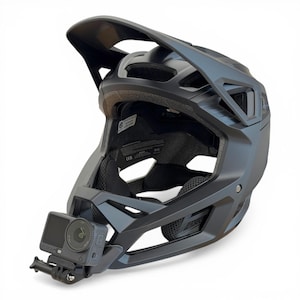 Könnte beinhalten: Mattschwarzer Mountainbike-Helm mit Visier und integrierter Kamerahalterung. Der Helm verfügt über mehrere Belüftungsöffnungen und ein gepolstertes Innenfutter. Eine kleine Action-Kamera ist vorne befestigt.