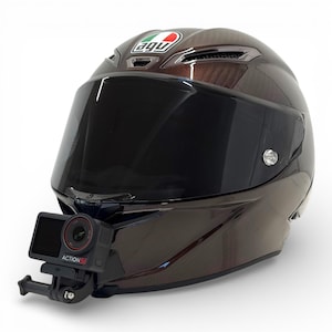 Pu&ograve; includere: Un casco da moto marrone con visiera scura e logo AGV. Una action camera nera &egrave; montata sulla parte anteriore del casco. Il casco ha una finitura lucida e prese d'aria.