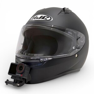 May include: Matte black motorcycle helmet with a clear visor and a mounted action camera. The helmet has the "HJC Helmets" logo on the top. The action camera is black and red, with the text "ACTION 5" visible.