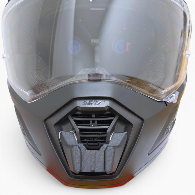 Puede incluir: Primer plano de un casco de moto negro con visera transparente. El casco tiene el nombre de la marca "LEATT" impreso en la parte delantera. La visera est&aacute; tintada y cubre la zona de la cara. El casco est&aacute; dise&ntilde;ado para protecci&oacute;n y seguridad.
