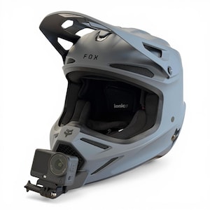 Könnte beinhalten: Grauer Fox-Rennhelm mit Visier und montierter Action-Kamera. Der Helm hat das Fox-Logo und das Wort "ionic" innen. Entwickelt für den Schutz bei Hochgeschwindigkeitsaktivitäten.