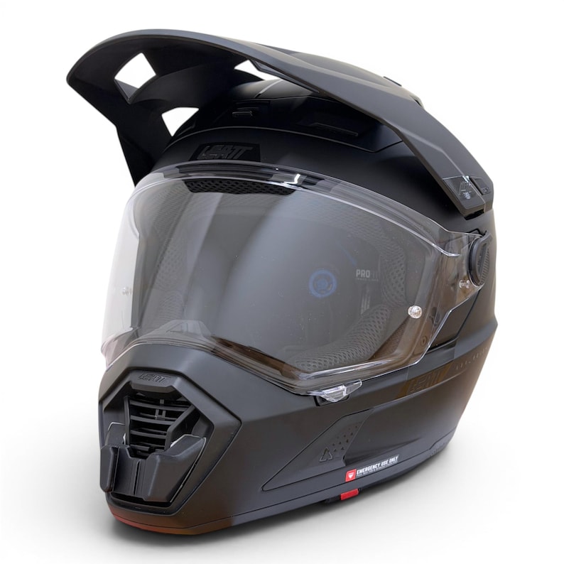 Puede incluir: Casco de moto negro mate con visera transparente. El casco tiene una visera prominente y elementos de ventilaci&oacute;n. La marca "LEATT" es visible. Dise&ntilde;ado para off-road o aventura.