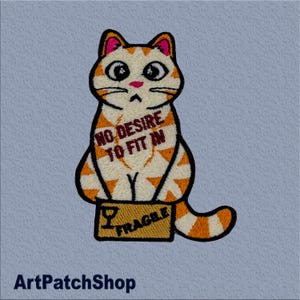 May include: Embroidered patch of a ginger and white cat with the text "NO DESIRE TO FIT IN." The cat sits on a brown box marked "FRAGILE." The patch has a light blue background. The patch is suitable for clothing.