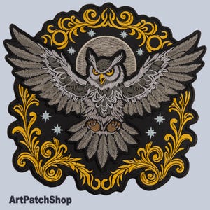 Könnte beinhalten: Gestickter Aufnäher mit einer detaillierten Eule mit ausgebreiteten Flügeln, vor einem schwarzen Hintergrund mit einem gelben Blumenrand und Sternen. Die Eule ist grau und weiß mit gelben Augen. Der Text "ArtPatchShop" steht unten.