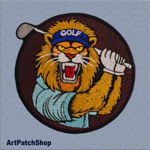 Op de afbeelding: Gestikt patch van een leeuw die een blauwe golfpet draagt en een golfclub vasthoudt. De leeuw heeft een woeste uitdrukking en draagt een blauw-wit shirt. Het patch is rond en heeft een rood-zwarte achtergrond.