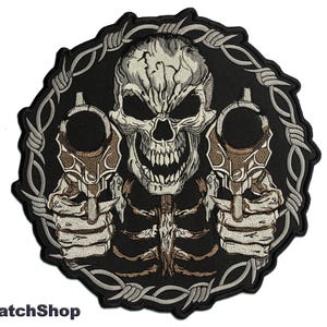 Puede incluir: Parche bordado con una calavera con una sonrisa amenazante que sostiene dos pistolas, rodeado de alambre de púas. La calavera es blanca y gris, las pistolas son marrones y el alambre de púas es plateado.