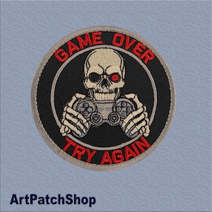 Op de afbeelding: Geborduurde patch met een schedel die een gamecontroller vasthoudt. De patch heeft de rode tekst "GAME OVER" en "TRY AGAIN". De schedel heeft een rood oog en staat tegen een zwarte achtergrond.