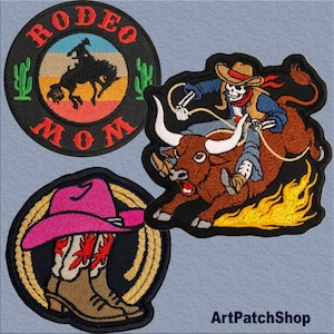 Könnte beinhalten: Drei gestickte Bügelbilder. Ein Patch zeigt einen Cowboy, der einen wilden Bronco reitet, mit den Worten "Rodeo Mom" in einem Kreis. Ein weiterer Patch zeigt einen Skelett-Cowboy, der einen wilden Stier reitet, mit Flammen, die aus den Hufen des Stiers kommen. Der dritte Patch zeigt einen rosafarbenen Cowboyhut und Stiefel mit einem Lasso.