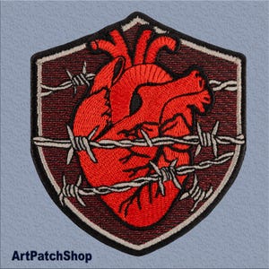 May include: Embroidered patch featuring a red heart surrounded by barbed wire, all within a shield-shaped design. The patch has a dark red background and white stitching.