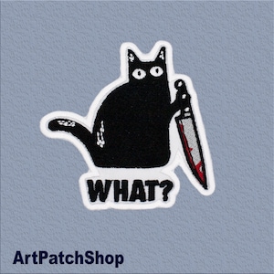 Op de afbeelding: Geborduurde patch met een zwarte kat die een bloedig mes vasthoudt. De kat heeft witte ogen en een witte omtrek. Het woord "WHAT?" staat onder de kat in witte, vette letters. Op een lichtblauwe, getextureerde achtergrond.