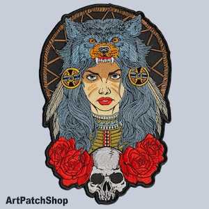 Puede incluir: Parche bordado con una mujer con un tocado de cabeza de lobo, rodeada de rosas rojas y una calavera. La mujer tiene ojos azules y cabello largo y oscuro. La cabeza de lobo es azul y gris con una lengua roja.