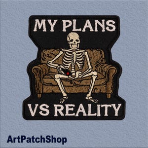 May include: Embroidered patch with the text "MY PLANS VS REALITY". The patch features a skeleton sitting on a brown couch. The skeleton has a red dot on its lap. The patch has a black border.