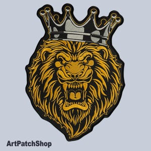 May include: A black and gold embroidered patch of a lion's head wearing a silver and black crown. The lion has a fierce expression with its mouth open and teeth showing.