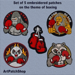 Puede incluir: Conjunto de cinco parches bordados con diseños de temática de boxeo. Los parches incluyen un gorila, un león, un panda, un mapache y un par de guantes de boxeo. Los parches son todos de forma circular y tienen un contorno negro. El texto "NO PAIN NO GAIN" está en el parche del león.
