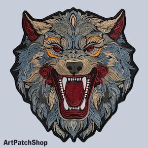 May include: Embroidered patch featuring a detailed wolf head with an open mouth, showcasing sharp white teeth. The design incorporates shades of blue, tan, red, and black, with the text "ArtPatchShop" at the bottom. The wolf's eyes are red.