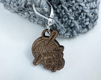 May include: A wooden yarn ball and knitting needle charm with floral accents attached to a silver-toned lobster clasp.
