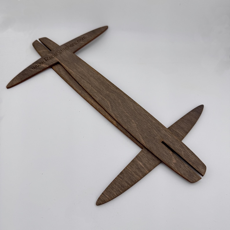 May include: A wooden tool with two arms that cross at a right angle. The arms are marked with a scale and the text "www.RabbitStitchery.com".