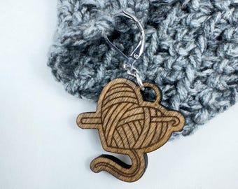 May include: A wooden yarn ball stitch marker with a heart shape and a crochet hook design. The marker is attached to a silver spring clasp.