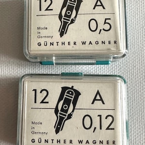 May include: Two small, clear plastic cases with green accents, each containing a white label with black text and a black graphic. The labels read "12 A 0,5" and "12 A 0,12", with "Made in Germany" and "GÜNTHER WAGNER" printed below.